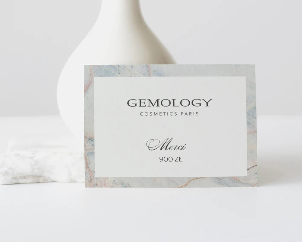 Karta podarunkowa Gemology Cosmetics Paris o wartości 900 zł. Na eleganckiej, jasnej karcie z marmurkową ramką widnieje napis „GEMOLOGY COSMETICS PARIS” oraz „Merci 500 zł”. Karta ustawiona jest na jasnym tle z minimalistyczną dekoracją w tle, podkreślając luksusowy charakter produktu.